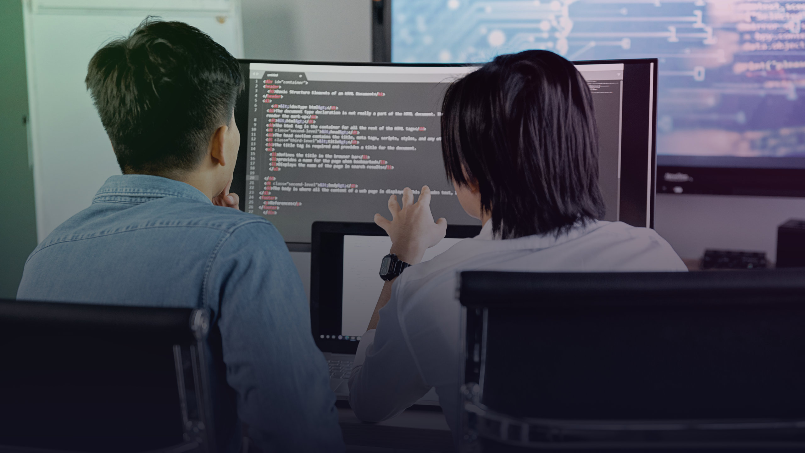 Zwei Entwickler betrachten Programmcode auf mehreren Bildschirmen.