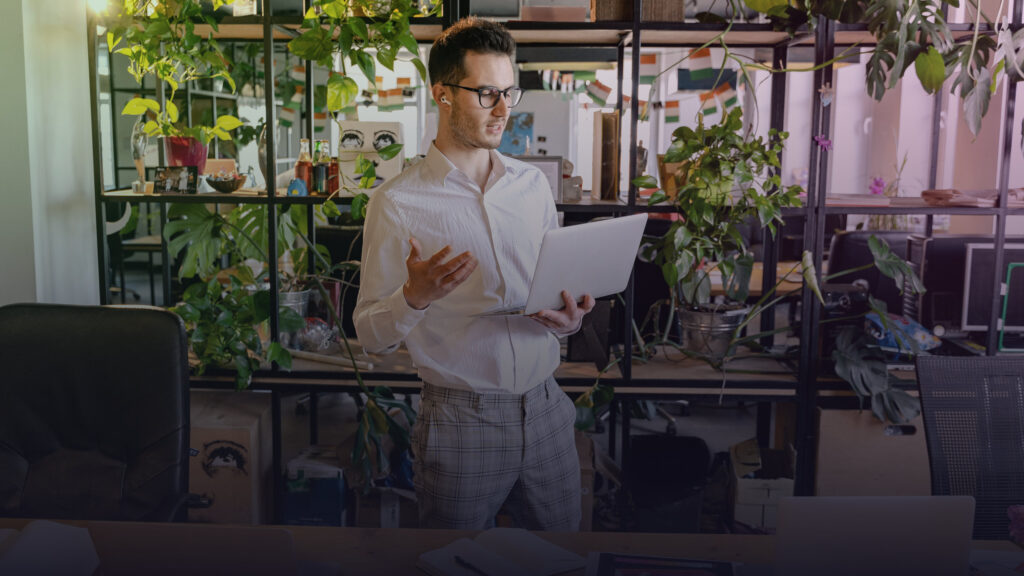 Mann arbeitet mit Laptop und Unterlagen in einem flexiblen Arbeitsumfeld.