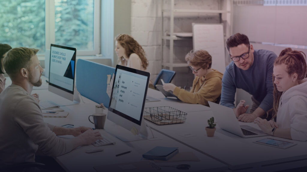 Team arbeitet gemeinsam an mehreren Computern im Büro.
