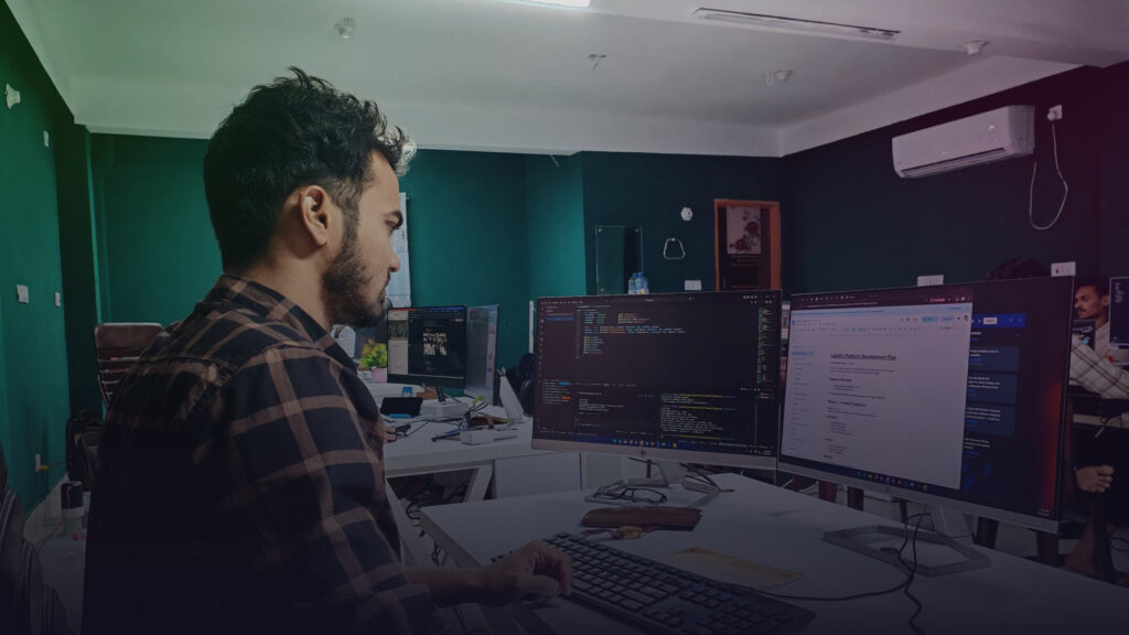 Entwickler arbeitet mit mehreren Monitoren und bespricht Code.
