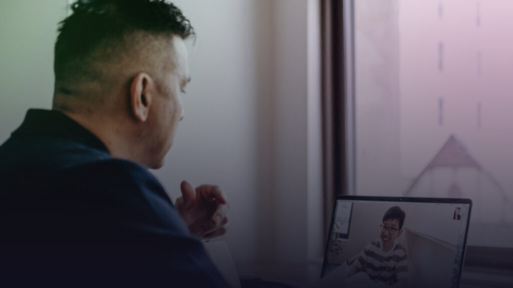 Mann bespricht sich per Videokonferenz mit einem Kollegen am Laptop.