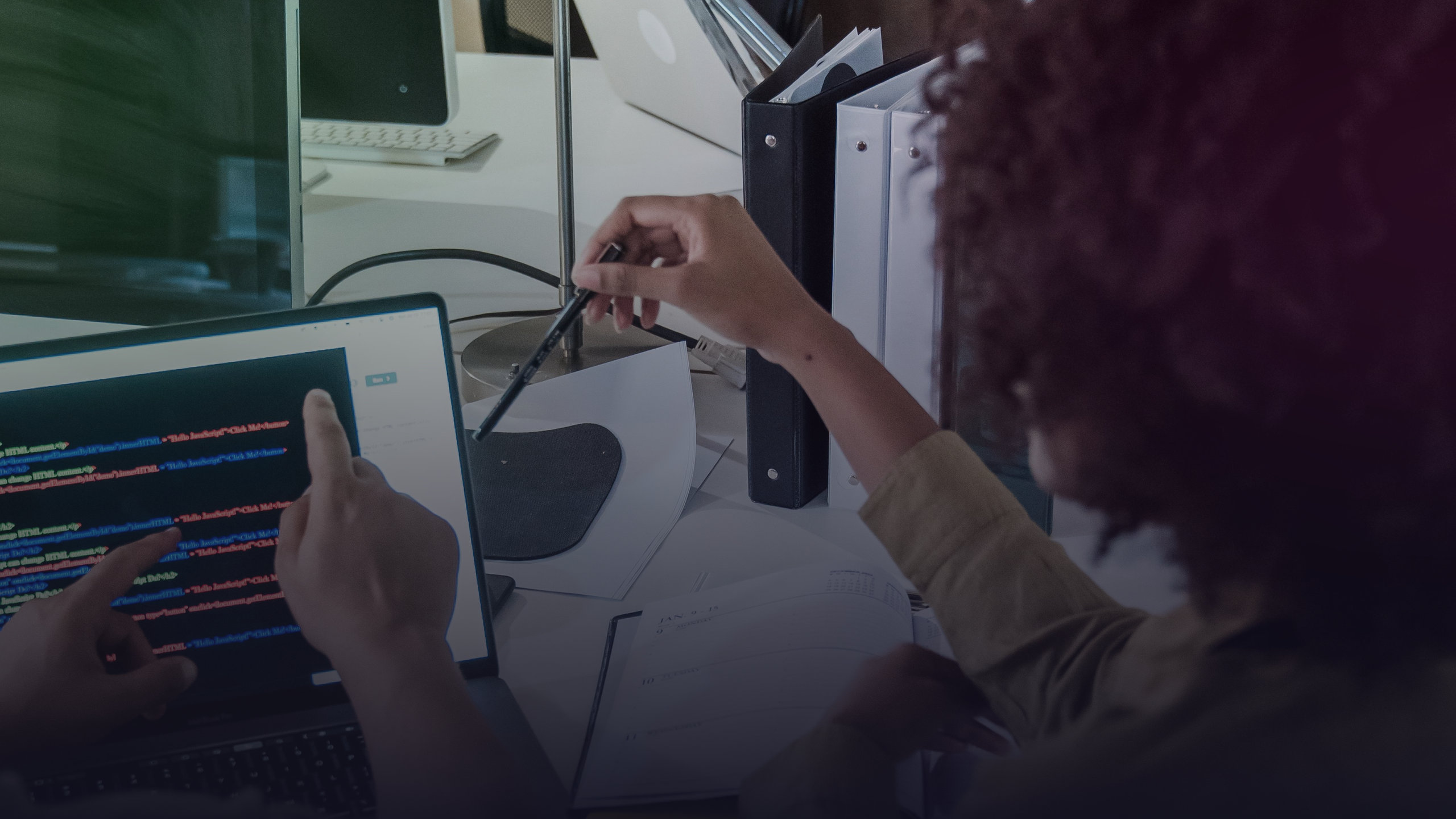 Entwicklungsteam prüft gemeinsam Programmcode an einem Bildschirm.
