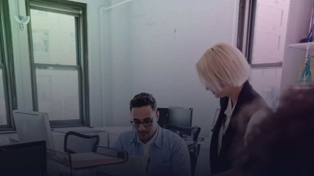 Kollegen tauschen sich an ihren Arbeitsplätzen im Büro aus.