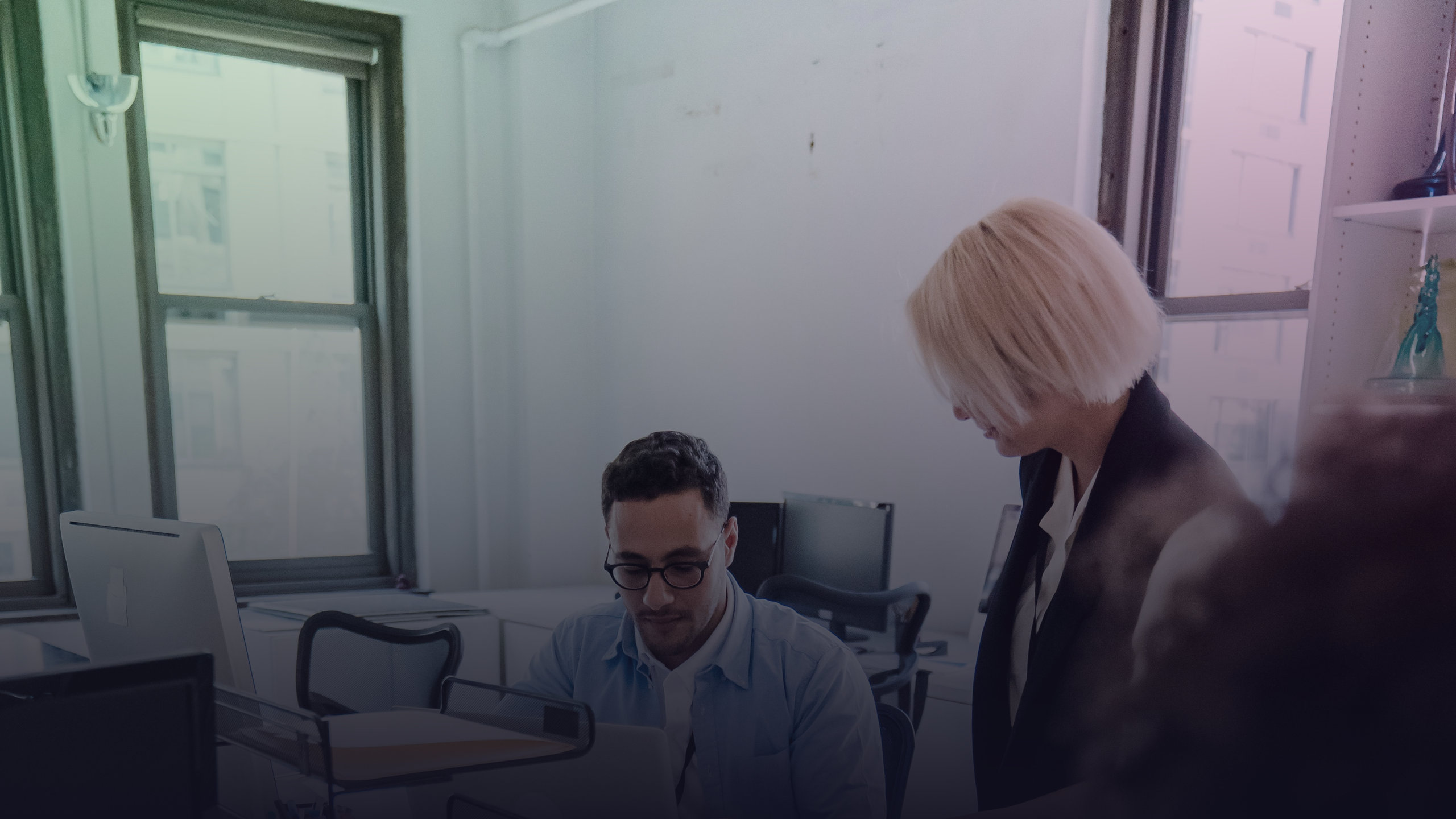 Kollegen tauschen sich an ihren Arbeitsplätzen im Büro aus.