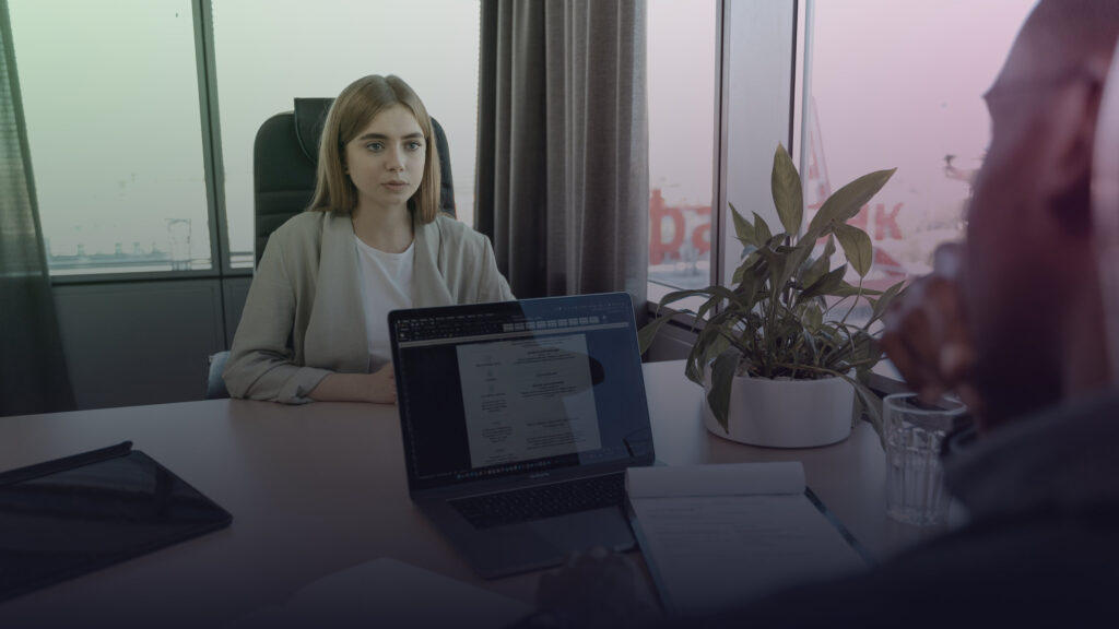 Bewerberin und Gesprächspartner besprechen Unterlagen am Tisch.