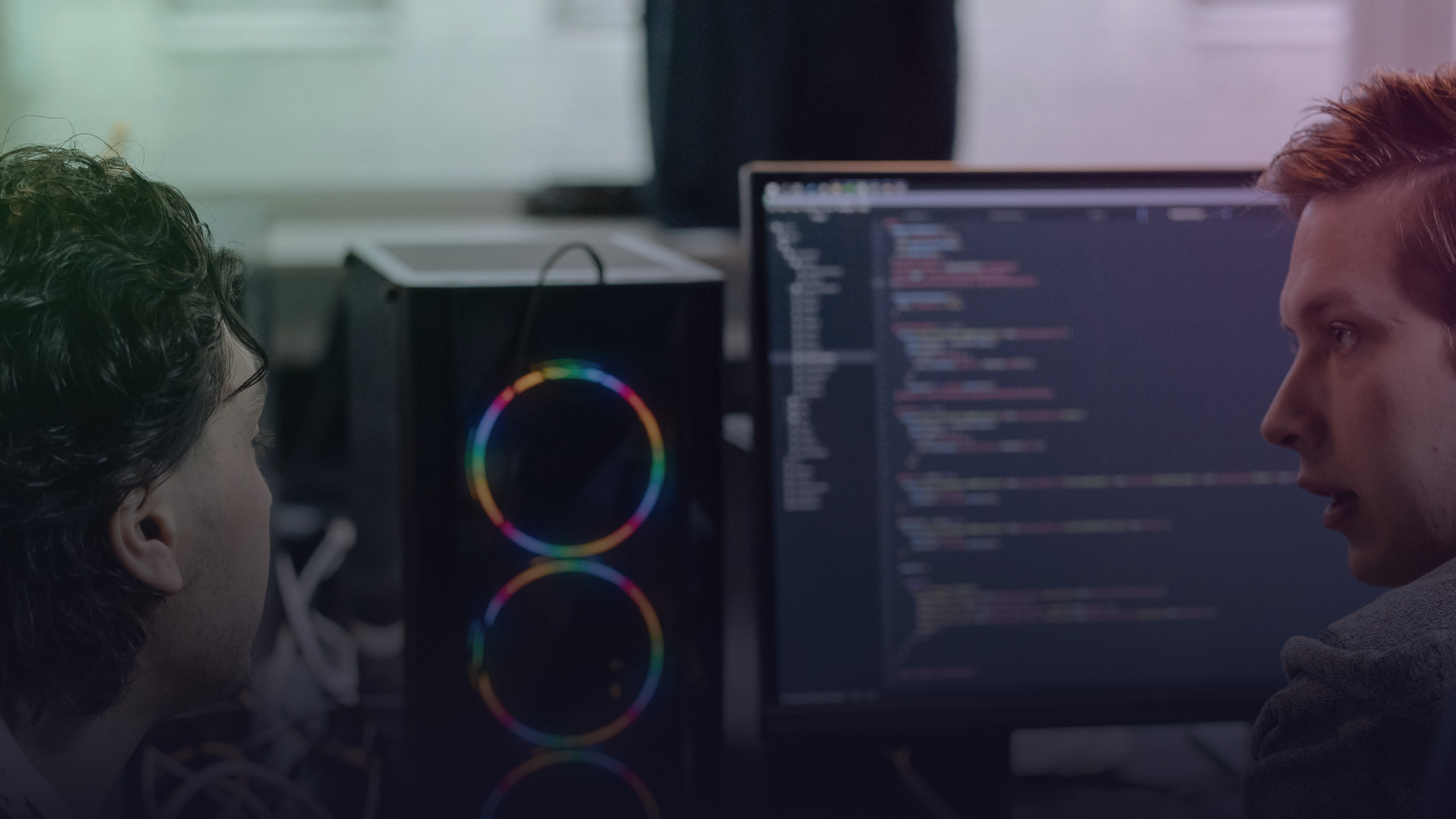 Zwei Entwickler besprechen Programmcode auf einem Bildschirm.