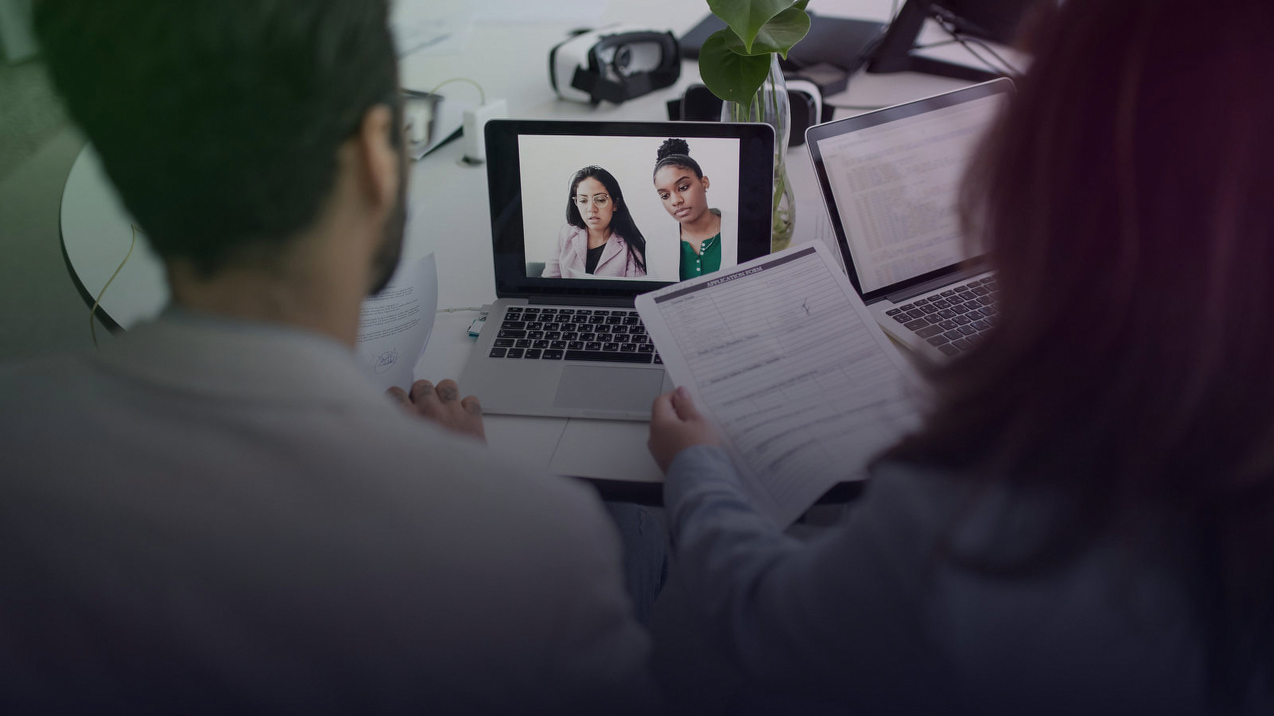 Two professionals conduct a virtual job interview over a laptop.