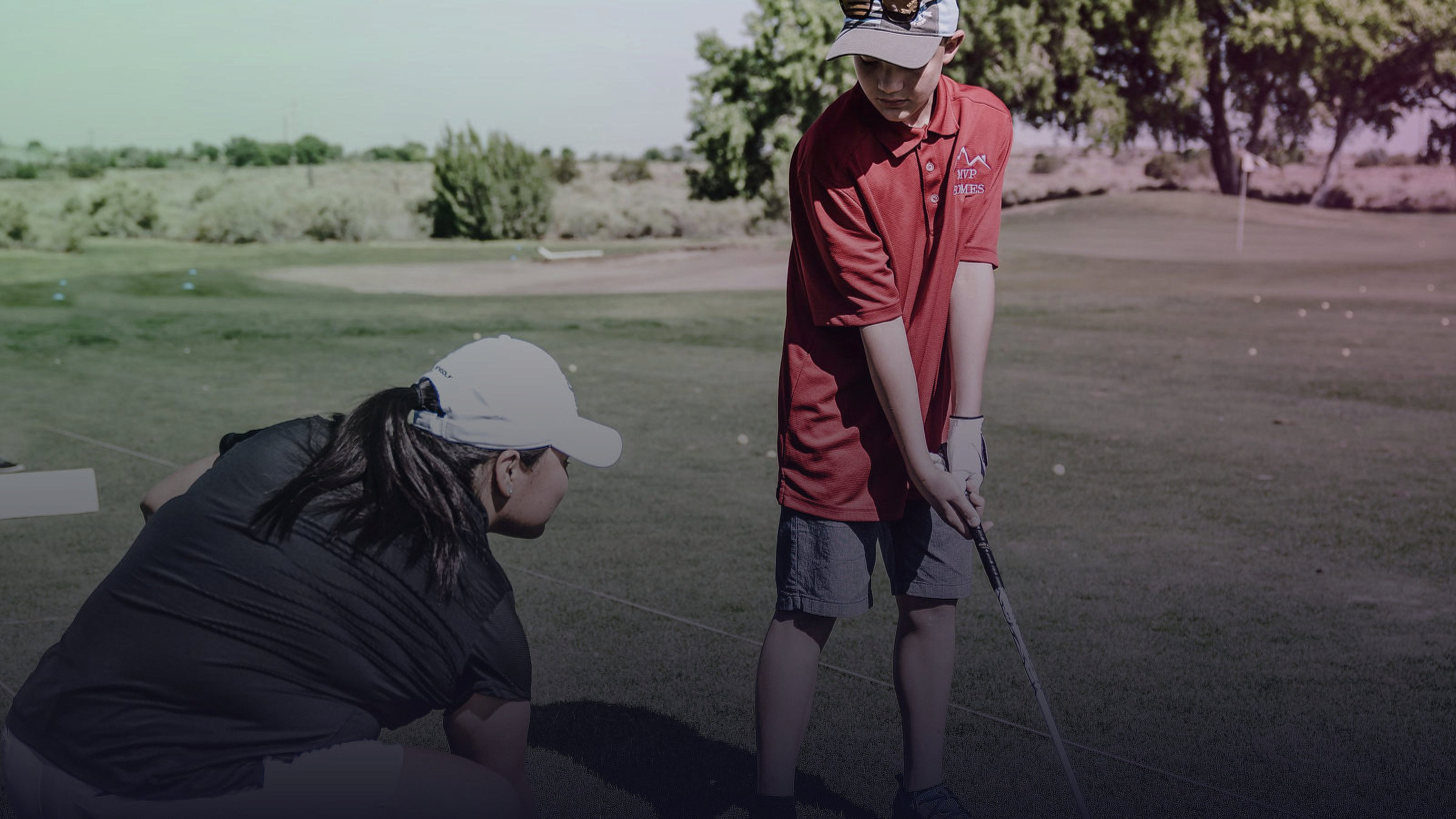 Eine Trainerin beobachtet einen jungen Golfspieler bei seinem Schwung.