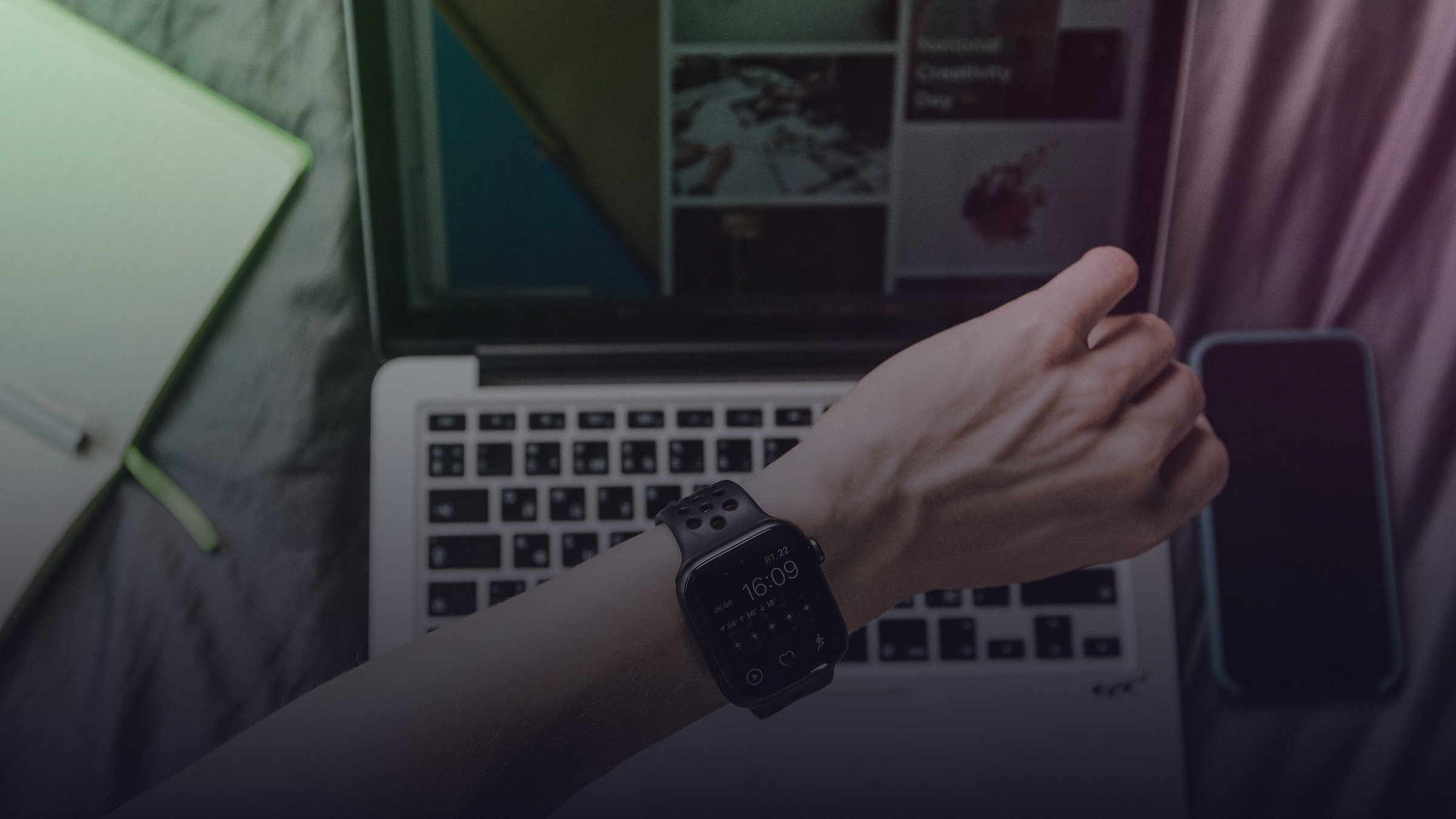 Eine Person trägt eine Smartwatch vor einem geöffneten Laptop.