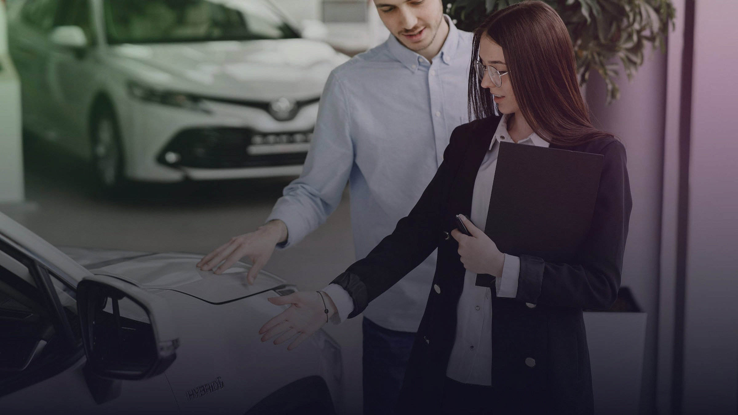 A man and a woman stand beside a vehicle in a car showroom.