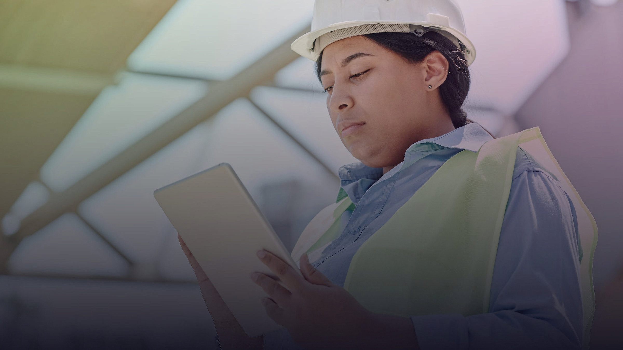 A construction worker wearing a hard hat uses a tablet.