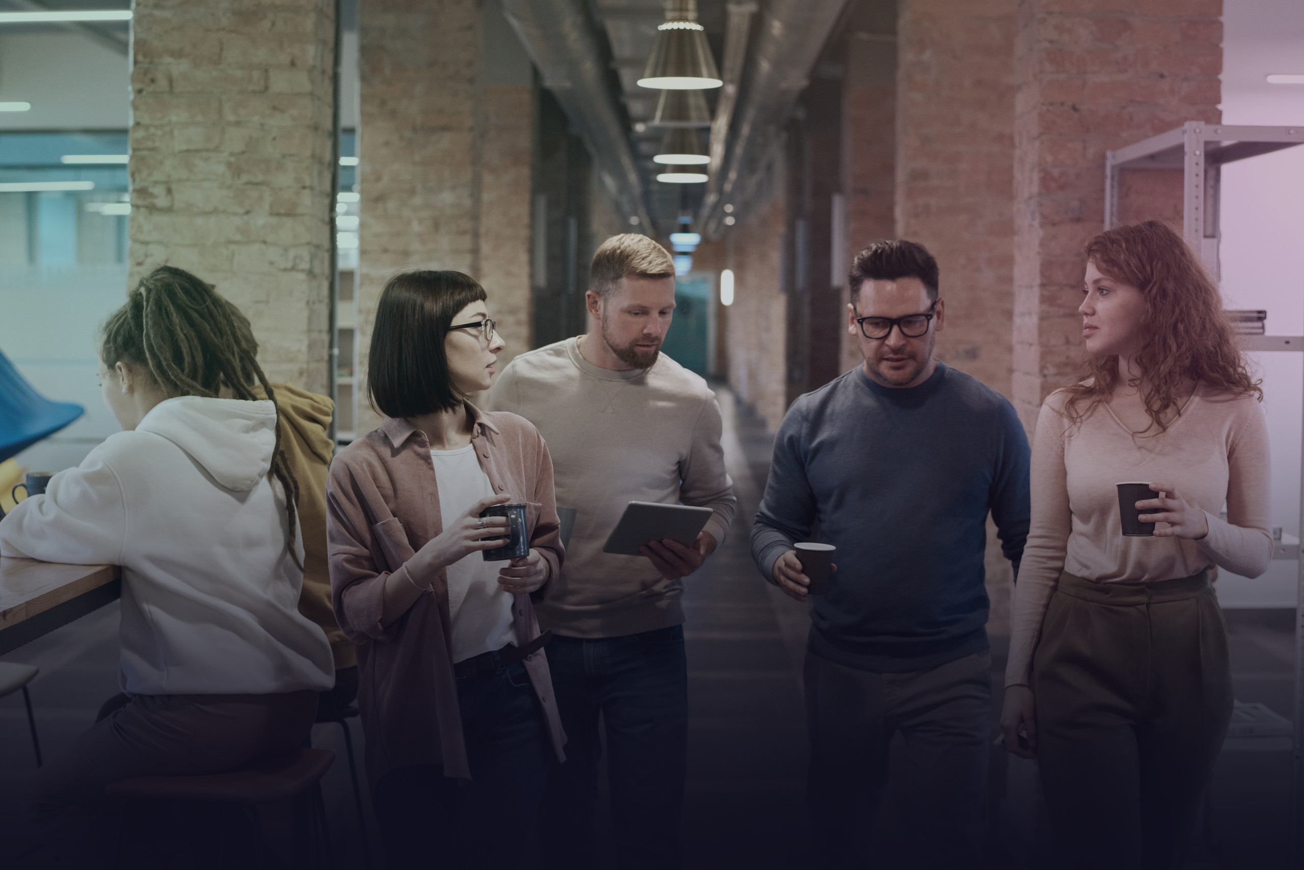 People talking with a tablet and coffee cups in a modern office.